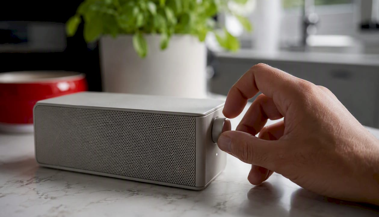 Χέρια που ρυθμίζουν τις λειτουργίες ενός Bluetooth ηχείου από κοντά.